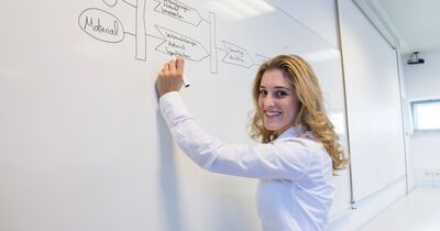 Eine Studentin steht vor einem Whiteboard.