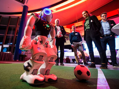 Das Bild zeigt einen Roboter, der Fußball spielt