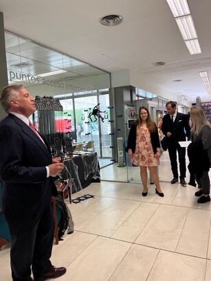 A man in a suit leads a small tour group inside a university building.