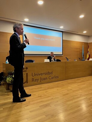 A man stands and gives a "Thank you very much!" speech with a microphone.