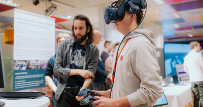 Ein Junge mit einer VR Brille und Joysticks probiert die virtuelle Welt aus