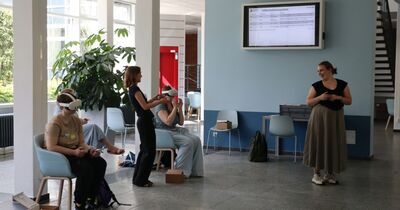 Auf zwei Stühlen sitzen Menschen mit VR Brillen auf.