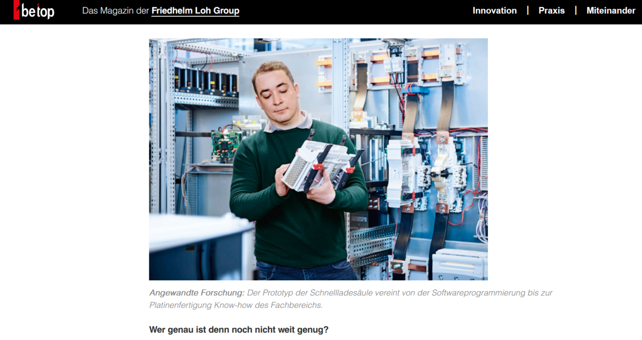 Person hält Prototyp einer Schnellladesäule in einem Technikraum mit Schaltschränken. Ausführliche Beschreibung im Element unterhalb.
