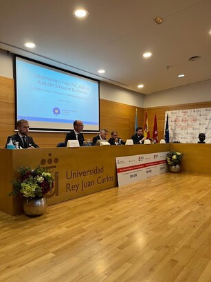A panel of speakers sits at a dais with a large prize check in front.