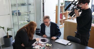 Zwei Menschen sitzen an einem Tisch und werden gefilmt.