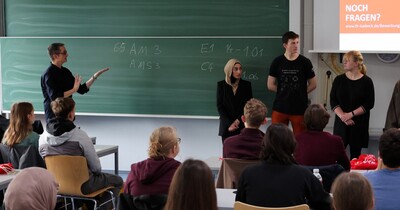 Studierende stehen vor einer grünen Tafel.