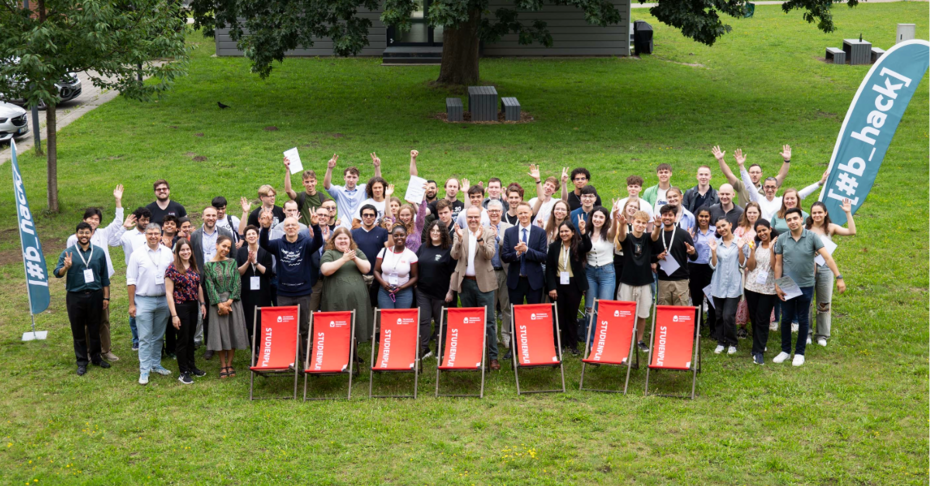 Gruppenbild von Menschen auf grünem Rasen mit roten Liegestühlen im Vordergrund