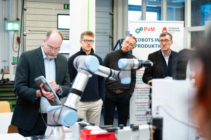 Mann steht mit Tablet hinter Cobot