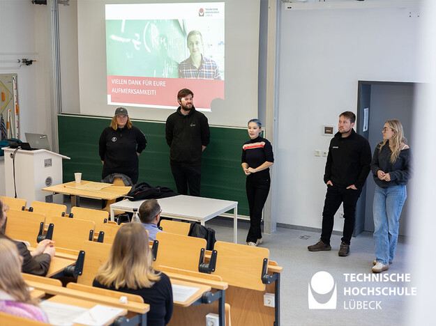Fünf Personen stehen neben Rednerpult und stellen sich vor