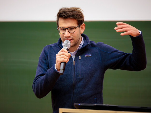 Rede vom Gewinner des Jahres 2021 Ein Mann mit Mikrofon im Hintergrund eine Tafel