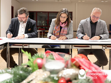 Georg Schareck, Muriel Helbig und Thorsten Freiberg unterzeichnen den Vertrag für die Holzbauprofessur. Foto: TH Lübeck 