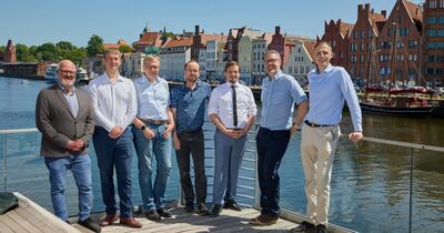 Sieben Männer stehen zusammen vor der Trave in Lübeck.