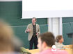 Mann steht vor Publikum und präsentiert