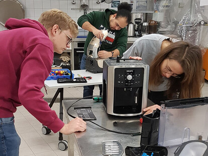 Begutachtung einer Kaffeemaschine Studierende der TH Lübeck schauen sich eine Kaffeemaschine von außen an.