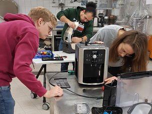 Studierende der TH Lübeck schauen sich eine Kaffeemaschine von außen an. 