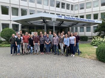 Exkursionsgruppe von Hörakustik-Studierenden der TH Lübeck vor dem Eingang des Deutschen HörZentrums (DHZ) in Hannover.