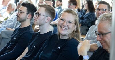 Eine Frau sitzt im Publikum und lächelt in die Kamera.