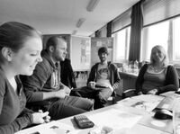 Schwarzweißfoto vier Studierende sitzen im Kreis und unterhalten sich