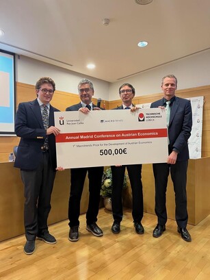 Four men hold up a large ceremonial prize check for 500,00€.