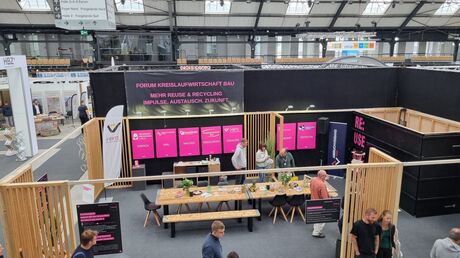 Überblick über den Messestand des Forums Kreislaufwirtschaft mit Sitzbereich und Infotafeln.