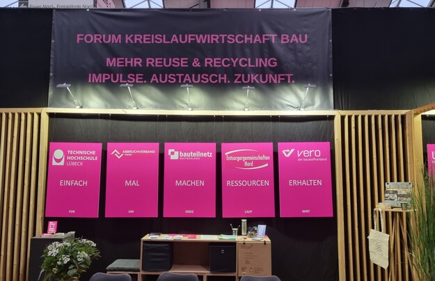 Pinkfarbene Infotafeln und ein großes Banner informieren über das Forum Kreislaufwirtschaft Bau.
