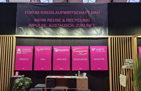 Pinkfarbene Infotafeln und ein großes Banner informieren über das Forum Kreislaufwirtschaft Bau.