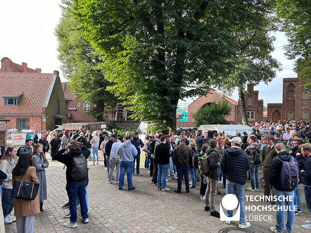 Studierende lernen sich im Kirchvorhof kennen Über 100 Studierende stehen im Freien des Kirchvorhofs