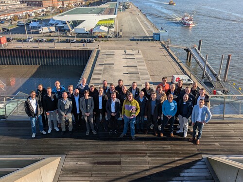 Gruppenfoto auf Treppe mit Blick auf Hafen, Terminal und Fähre.