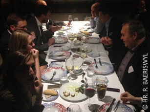 A group of people in business attire at a dinner at a long table.