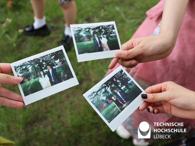 Studierende knipsen Polaroidfotos Drei Polaroidfotos werden in die Kamera gehalten
