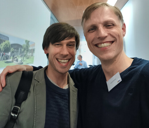 Selfie von zwei lachenden Teilnehmenden im Flur einer Tagungsveranstaltung.