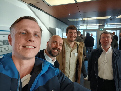 Selfie von vier Teilnehmenden in heller Lobby eines Konferenzgebäudes.