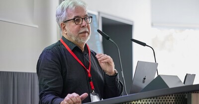 Ein Mann steht an einem Rednerpult in einem Hörsaal.