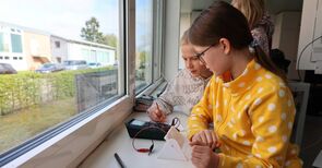 Zwei Mädchen lesen Strom von einem Messgerät ab.