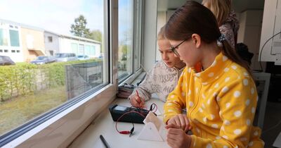 Zwei Mädchen lesen Strom von einem Messgerät ab.