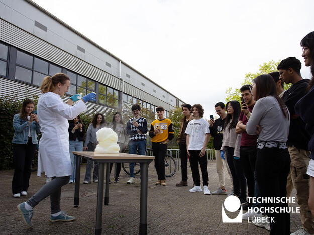 Elephant Toothpaste Reaktion im vollen Gange Eine Frau steht vor einem Tisch, auf dem Tisch ein chemisches Experiment