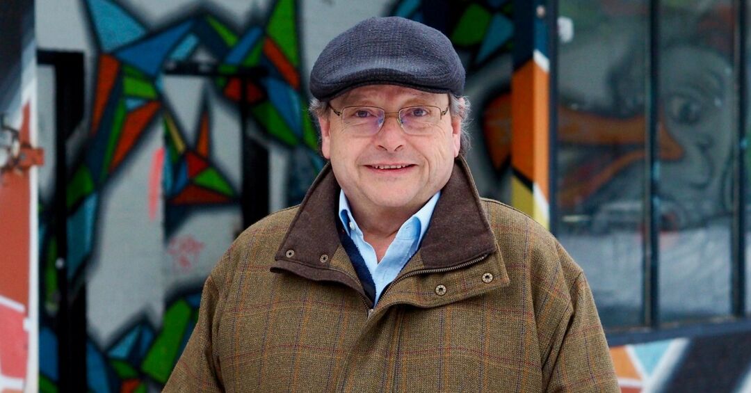 Prof. Manfred Rößle vor einer bunten Wand