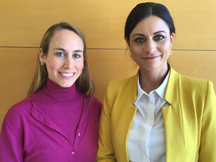 Portrait of two smiling women, one in a magenta top, one in a yellow blazer.
