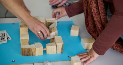 Auf einem Tisch werden unterschiedliche Holzstücke zusammengelegt.