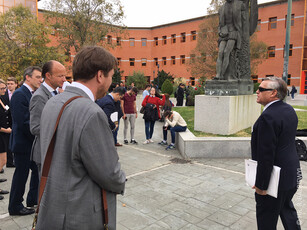 A group of people standing and talking on an outdoor university campus.