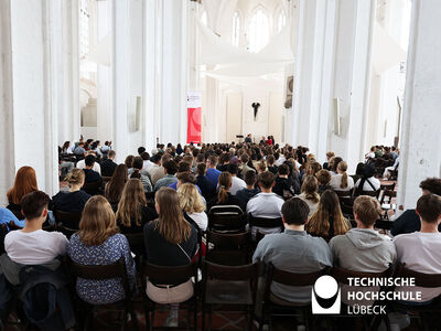 Viele Menschen sitzen in Reihen in einer weißen kirche, man sieht ihre Hinterköpfe
