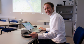 Ein Mann in einem weißen Hemd sitzt vor einem Laptop