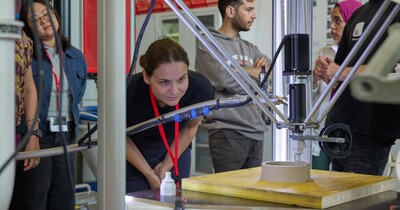 Eine Frau schaut einem 3D-Drucker bei der Arbeit zu.