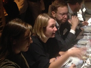 Three people sitting at a table during a dinner, engaged in conversation.