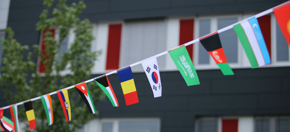 Internationale Fähnchen an einer Leine im Wind. ImHintergrund ein Gebäude der TH Lübeck.