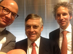 A selfie of three men in suits and ties smiling at the camera.
