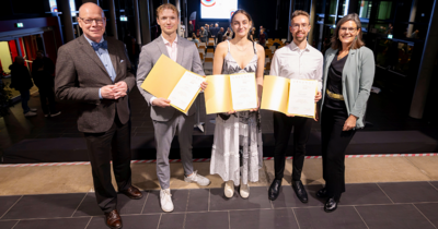 5 Personen in einer Reihe, drei mit einer goldenen Urkunde