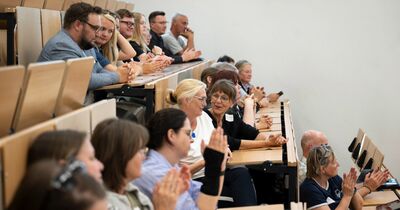 MINT-Schulen-Akkreditierung_1 Zuhörer im Hörsaal klatschen und unterhalten sich.