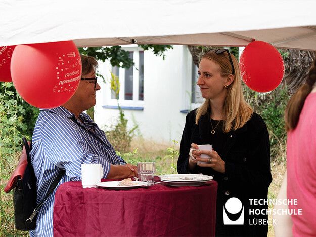 Bergfest beim Mentoringprogramm Zwei Personen stehen an einem Stehtisch und unterhalten sich