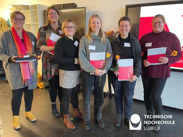 Danksagung der TH Kanzlerin Sechs Frauen auf einem Bild, winterlich gekleidet, mit Urkunden und Blumen in der Hand